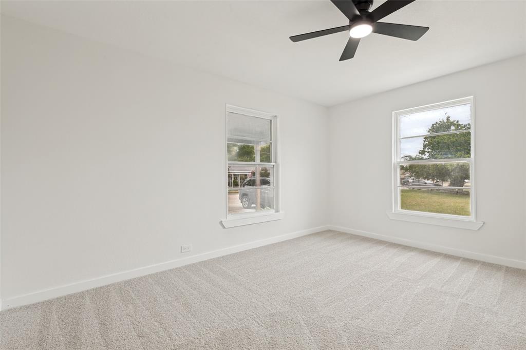 Carpeted room with two large windows and a ceiling fan with integrated lighting
