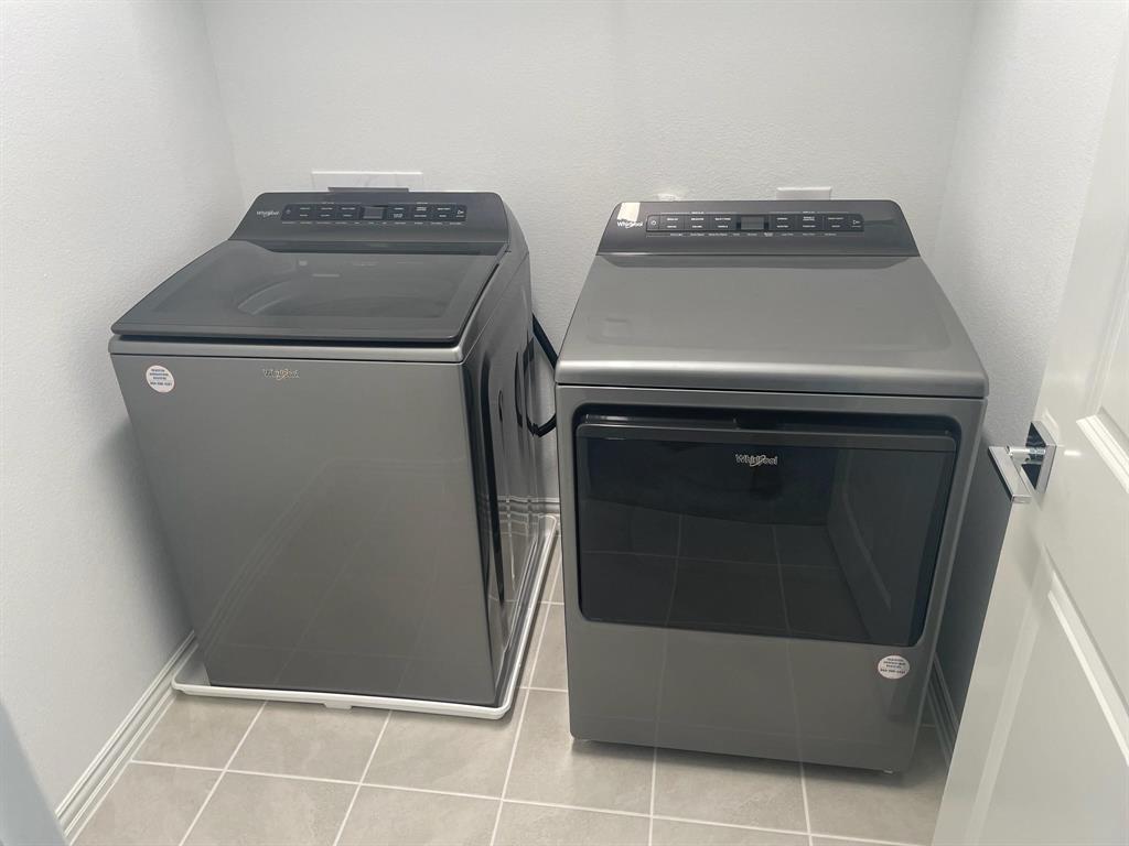 Dedicated laundry area featuring a top-load washer and front-load dryer in a neutral finish