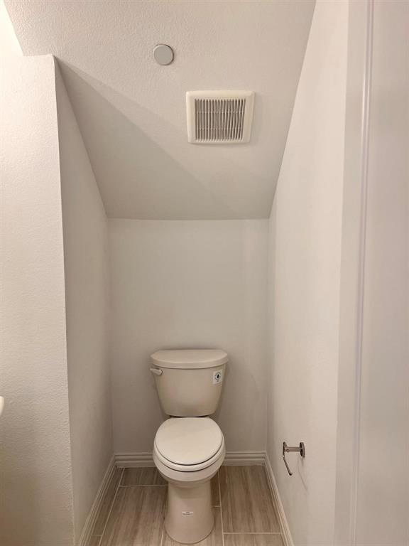 Powder room featuring a single toilet, wood-look tile flooring, and a ceiling-mounted exhaust fan