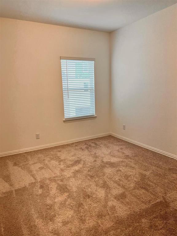 Room featuring neutral-toned walls, a single window with horizontal blinds, and tan carpet flooring