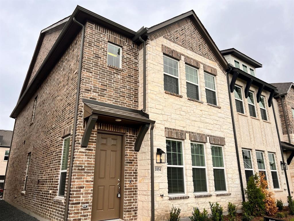Multi-story townhome featuring a stone and brick facade