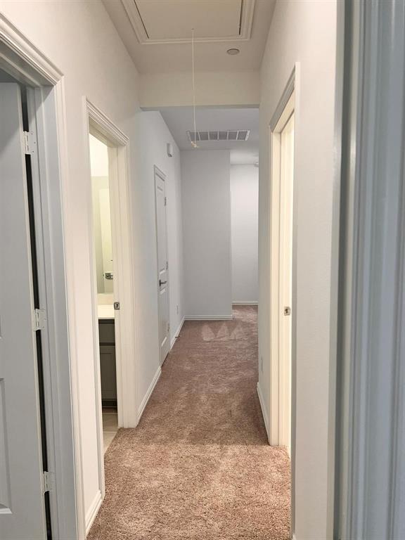 Carpeted hallway featuring white walls and baseboards