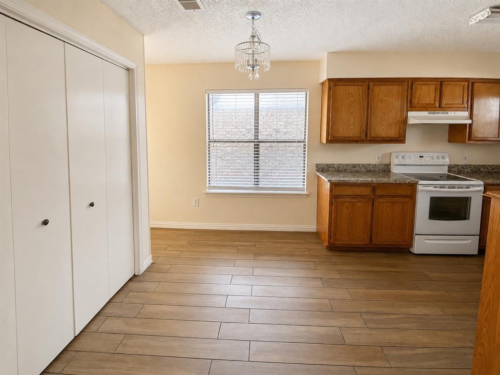 Kitchen space featuring wood-finish flooring, oak cabinetry, and granite-look countertops Kitchen space featuring wood-finish flooring, oak cabinetry, and granite-look countertops