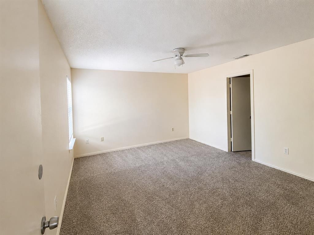 Spacious room featuring new carpet, a ceiling fan, and ample natural light from the window