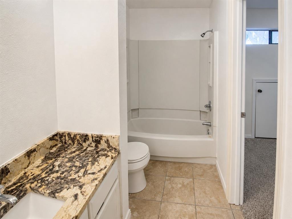 Bathroom featuring a vanity with a patterned stone countertop, an integrated sink, and white cabinetry Bathroom featuring a vanity with a patterned stone countertop, an integrated sink, and white cabinetry