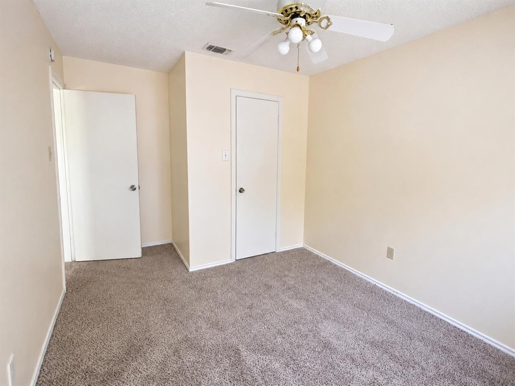 Carpeted room featuring a ceiling fan with light fixture, neutral-toned walls, and two white panel doors