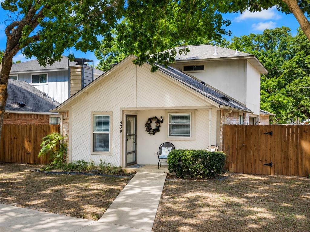 Gable roofline property featuring a front walkway, established trees, and wood fencing