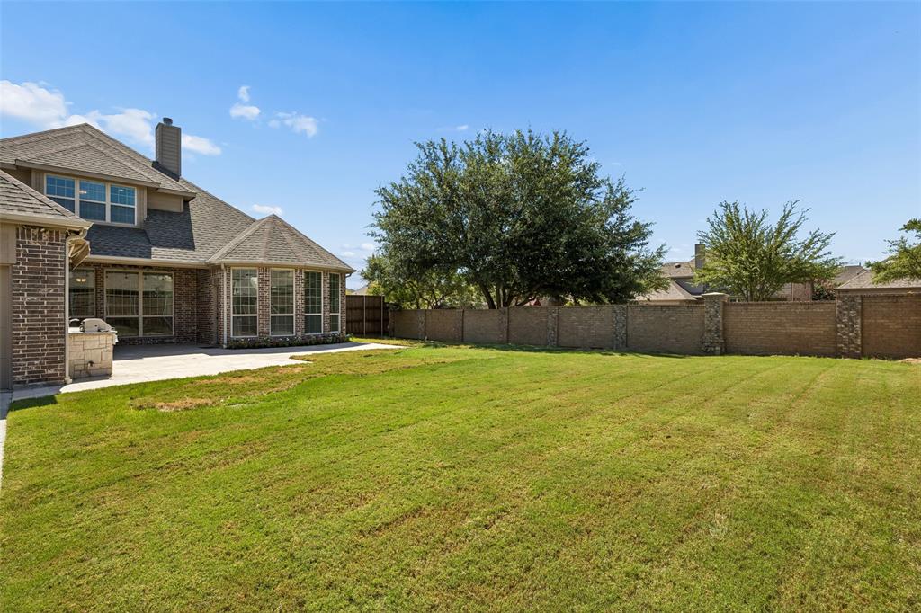 Expansive green lawn with a privacy wall