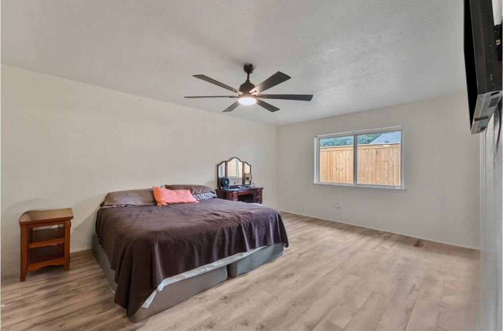 Recessed window with wood-framed glass, wood-finish flooring, and a ceiling fan with integrated lighting
