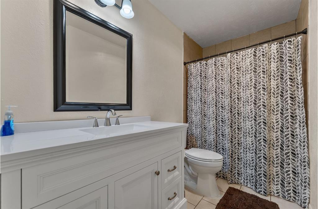 White vanity with an integrated sink, brushed nickel faucet, and framed mirror