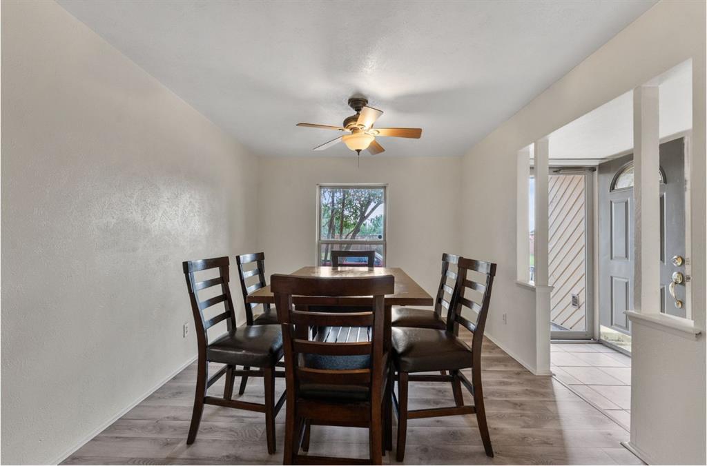 Wood-finish flooring throughout, ceiling fan with integrated lighting, and a window providing natural illumination