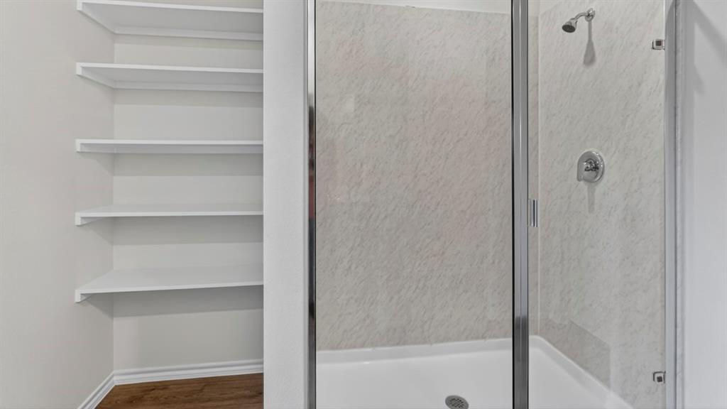 Built-in shelving unit alongside a glass-enclosed shower with a chrome showerhead and control