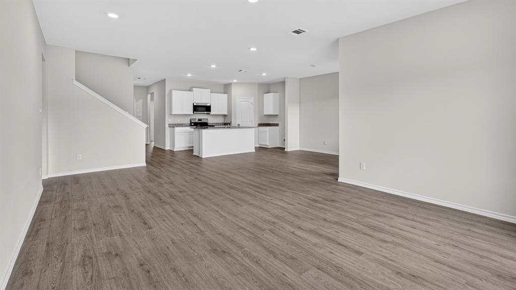 Expansive open-concept living area featuring wood-finish flooring, recessed lighting, and a neutral wall palette