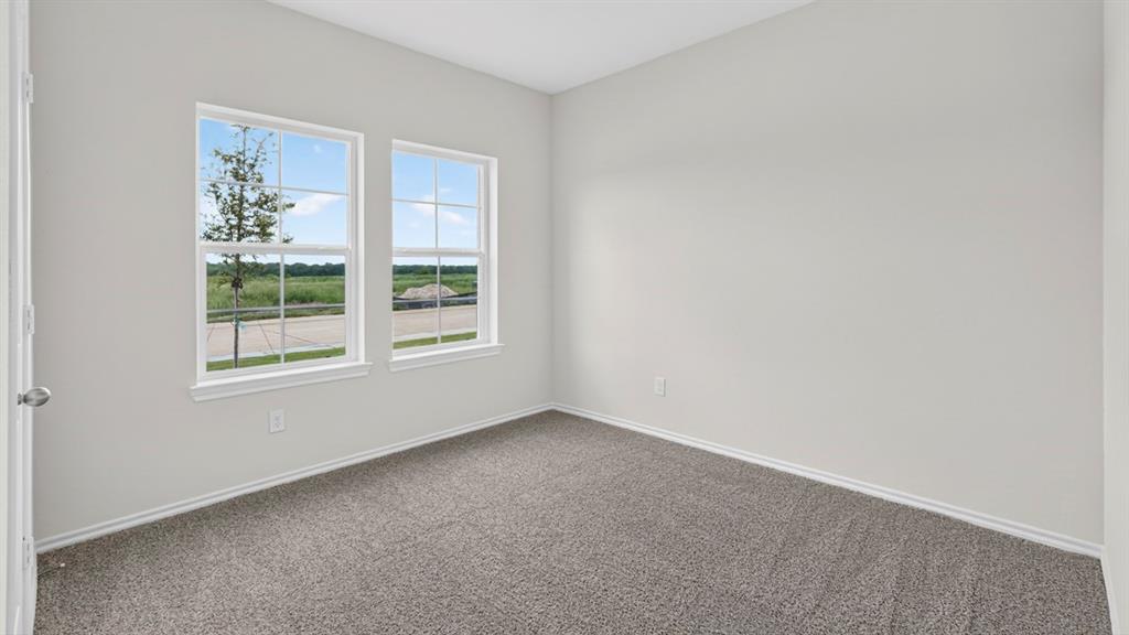 Light-filled room featuring two multi-pane windows, neutral wall tones, and gray carpeting