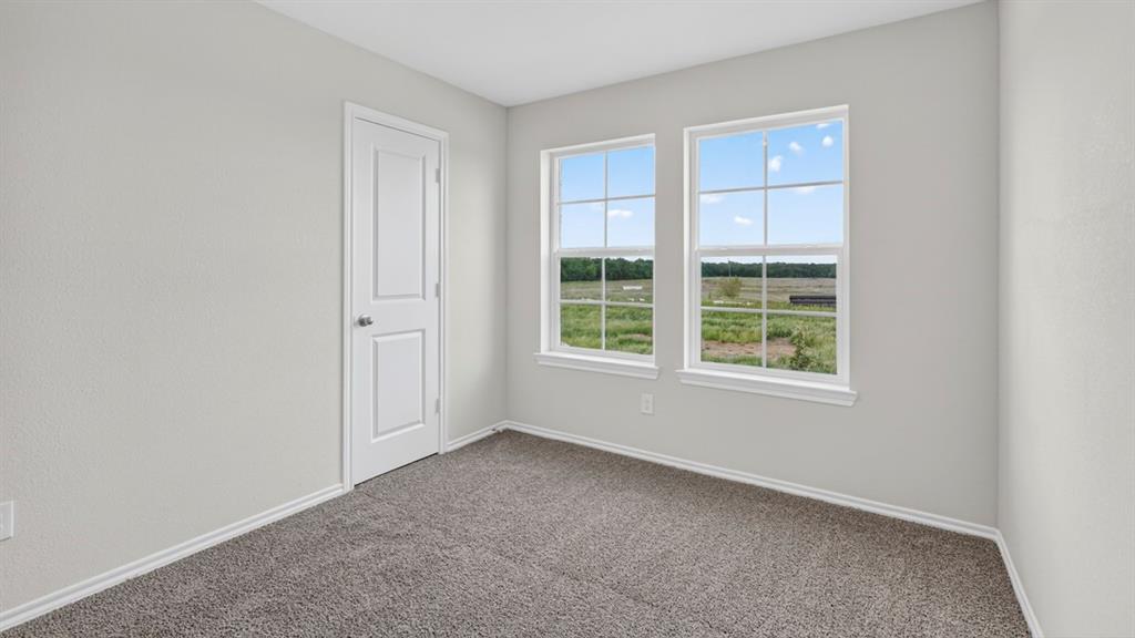 Room with light gray walls, gray carpet, and two large windows offering extensive outdoor scenery