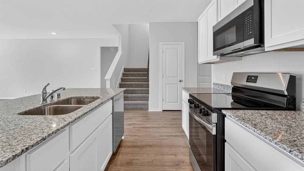Kitchen featuring white cabinetry, stainless steel appliances, a double basin sink, and wood-finish flooring