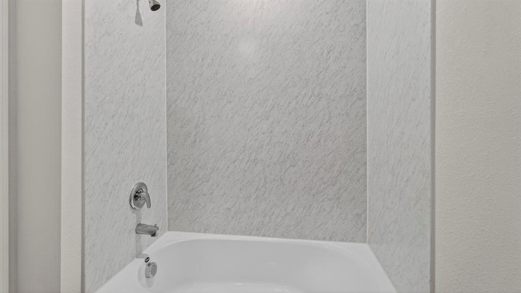 White tub-shower combination featuring a chrome shower head and faucet