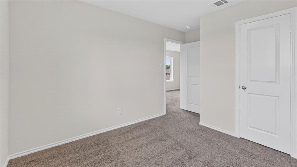 Carpeted interior room with light gray walls, white trim, and a white paneled door with a silver knob