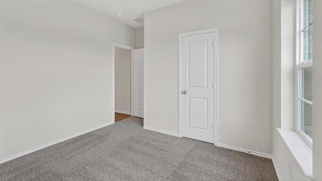 Carpeted interior room featuring light gray walls, white trim, a single window, and a paneled door