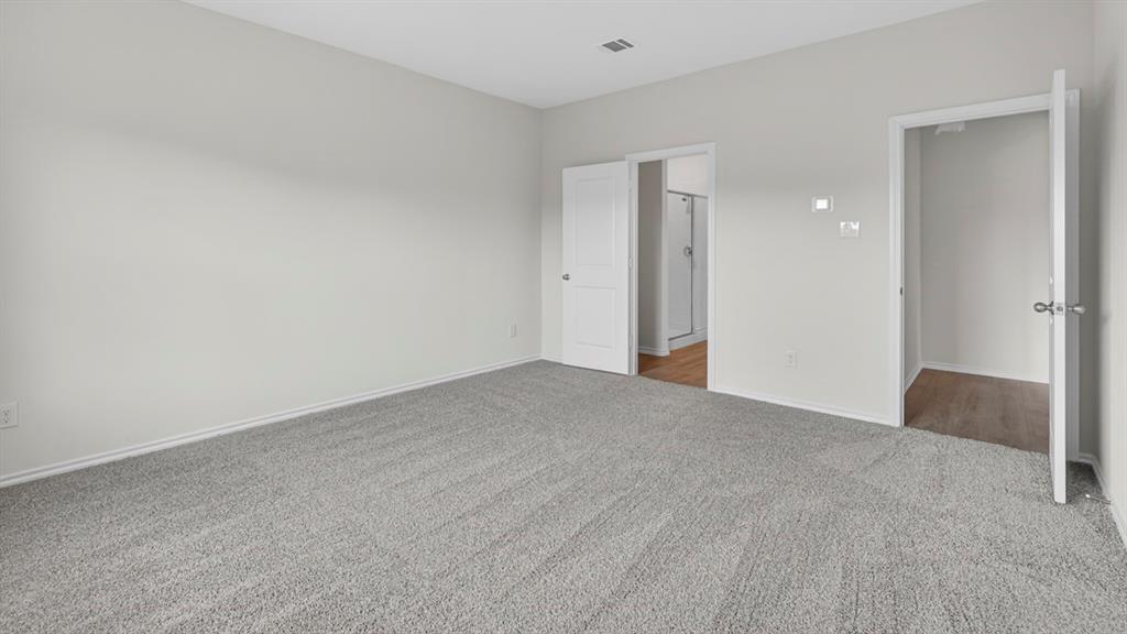 Spacious room featuring light gray walls, gray carpet flooring, and white trim
