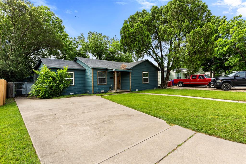Single-story residence featuring a dark blue siding exterior, a gray shingle roof, and multiple white-trimmed windows Single-story residence featuring a dark blue siding exterior, a gray shingle roof, and multiple white-trimmed windows