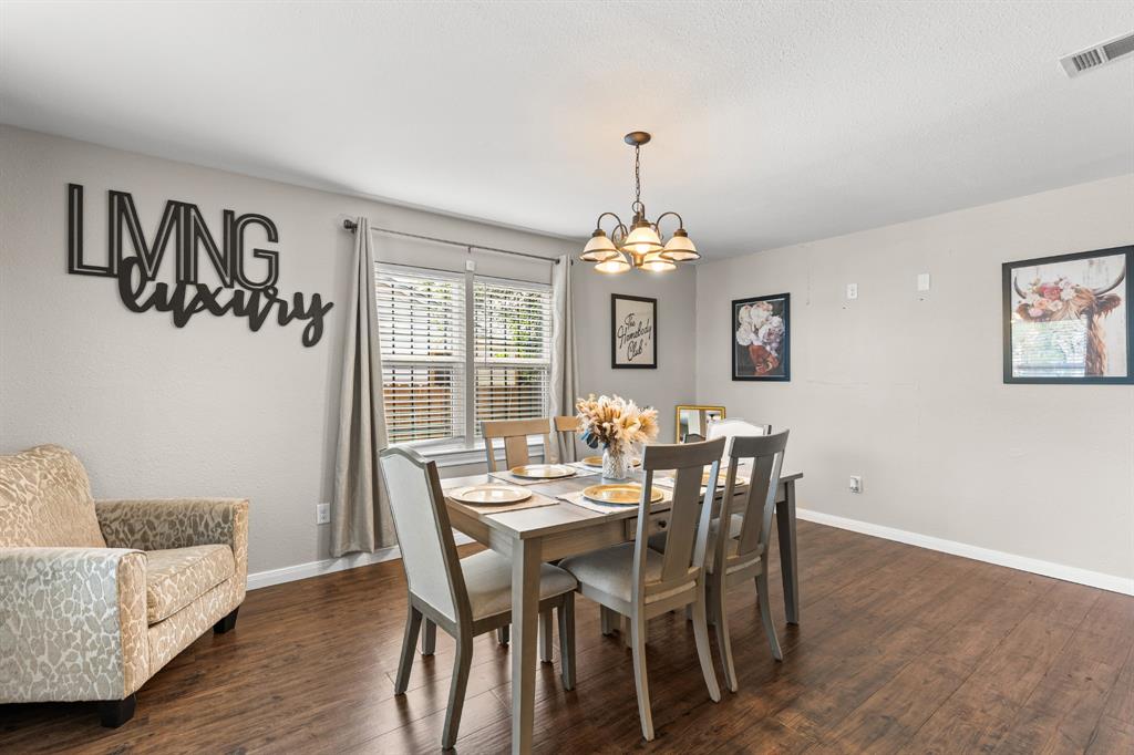 Dining area featuring wood-finish flooring, neutral wall tones, and a multi-bulb chandelier Dining area featuring wood-finish flooring, neutral wall tones, and a multi-bulb chandelier
