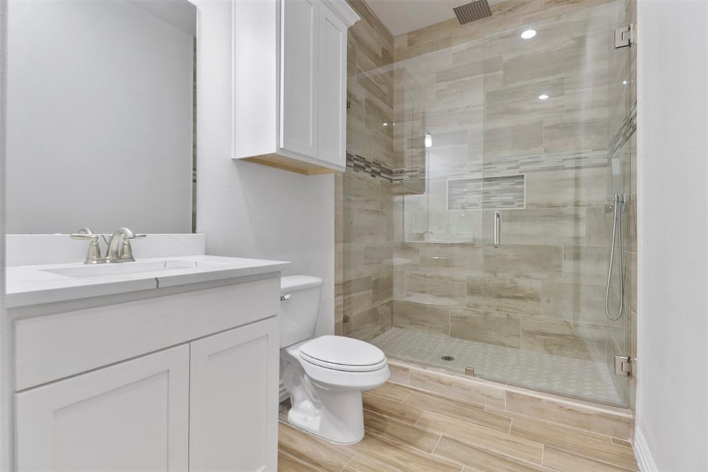 Bathroom featuring a glass-enclosed shower with tile surround, a built-in shower niche, and a rain shower head