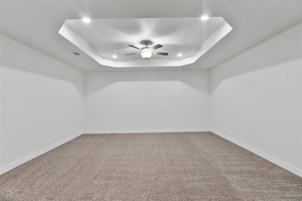 Spacious room featuring fresh white walls, neutral carpet flooring, and a modern recessed ceiling with integrated ceiling fan and recessed lighting throughout