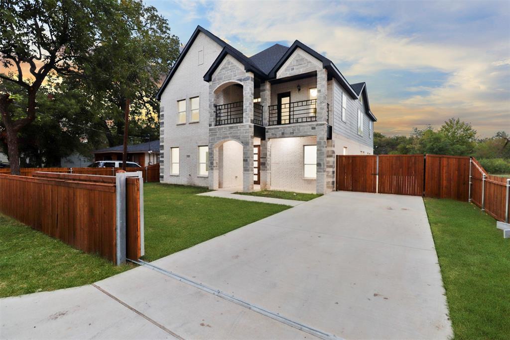 Modern two-story residence featuring a striking architectural design with peaked rooflines, white exterior cladding, and dark stone accents