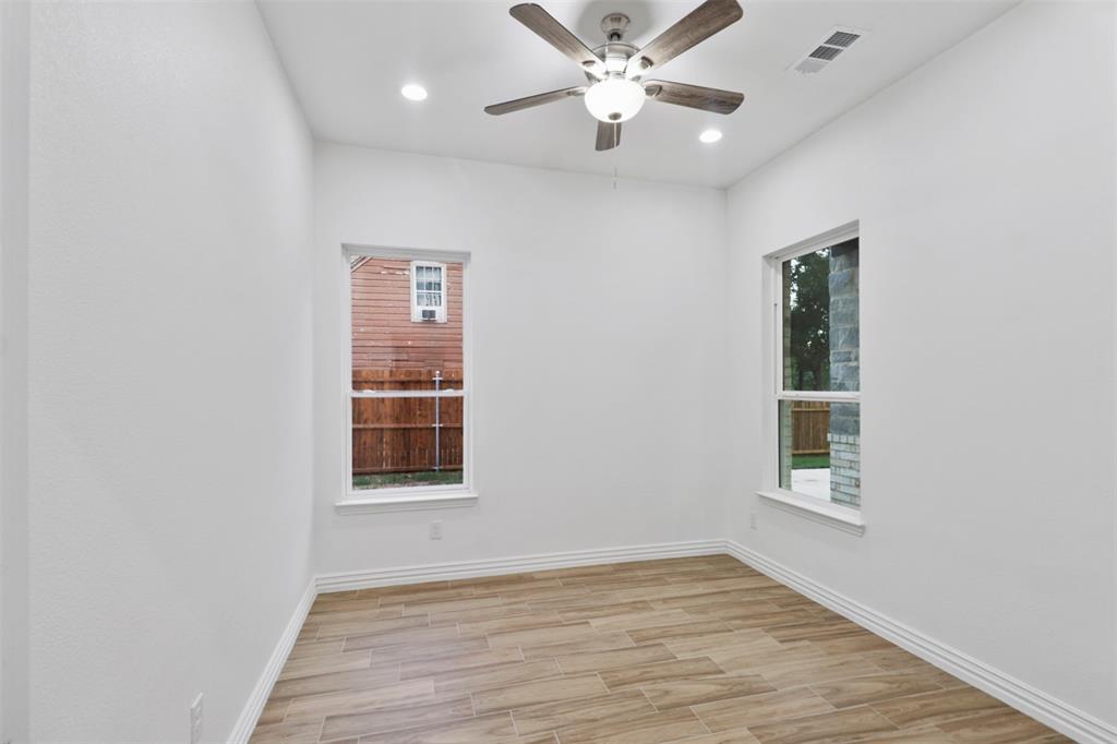 Bright, airy bedroom featuring gleaming wood-finish flooring, fresh white walls, and abundant natural light from two large windows