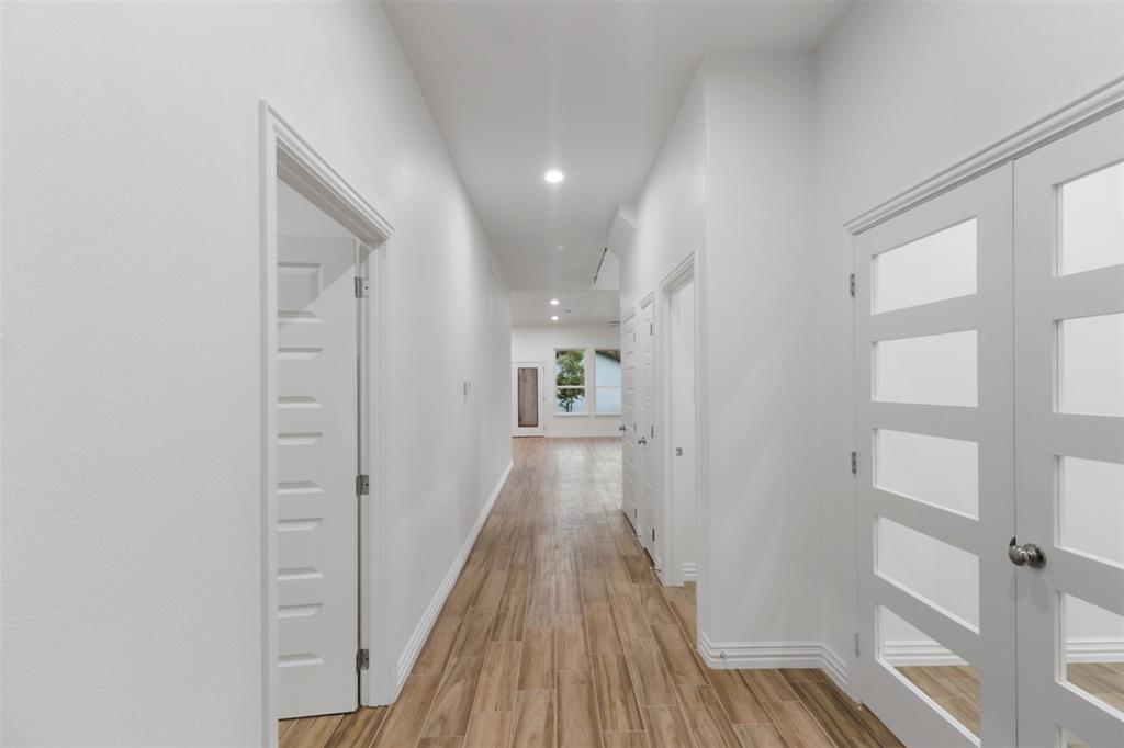 Elongated hallway featuring wood-finish flooring, recessed lighting, and white baseboards