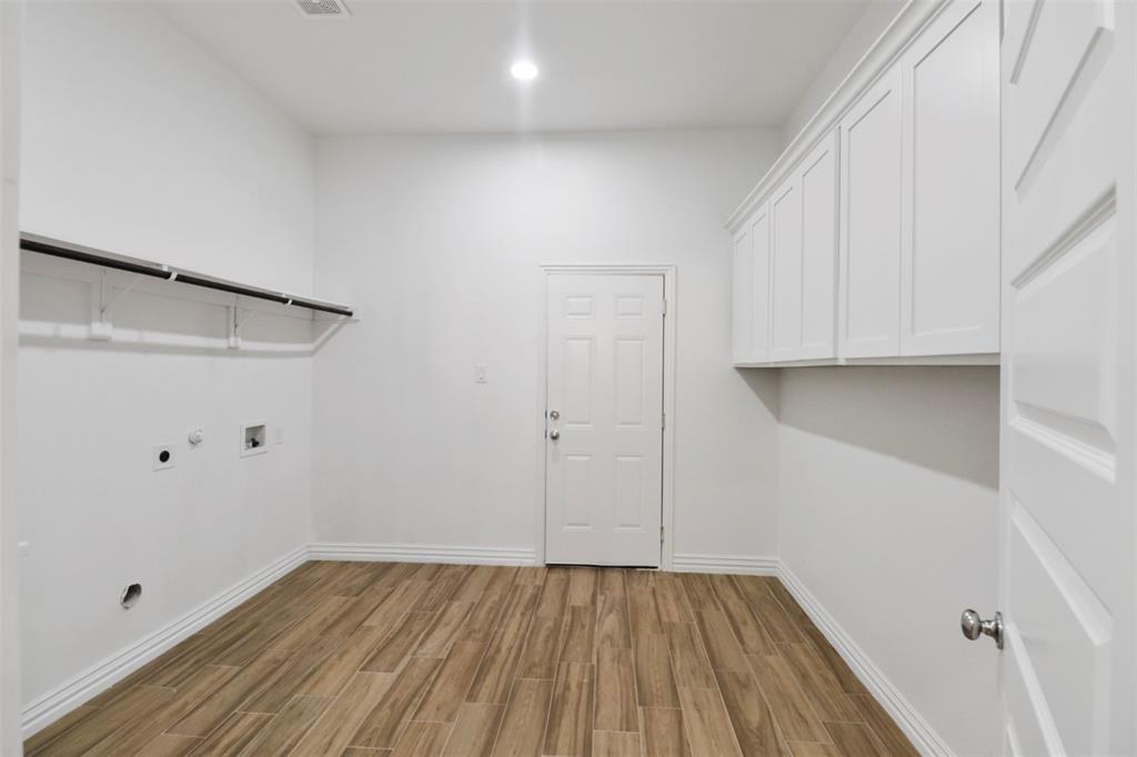 Laundry room featuring wood-finish flooring, white cabinetry, integrated lighting, and a built-in hanging rod