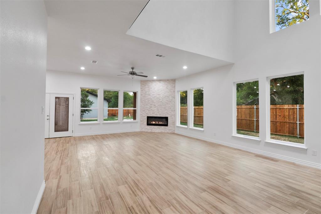 Spacious open-concept living area featuring soaring ceilings with skylight, wood-finish flooring throughout, and multiple sets of glass French doors opening to outdoor space