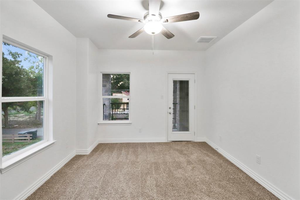 Carpeted room featuring a ceiling fan, two windows, and a glass-paneled door
