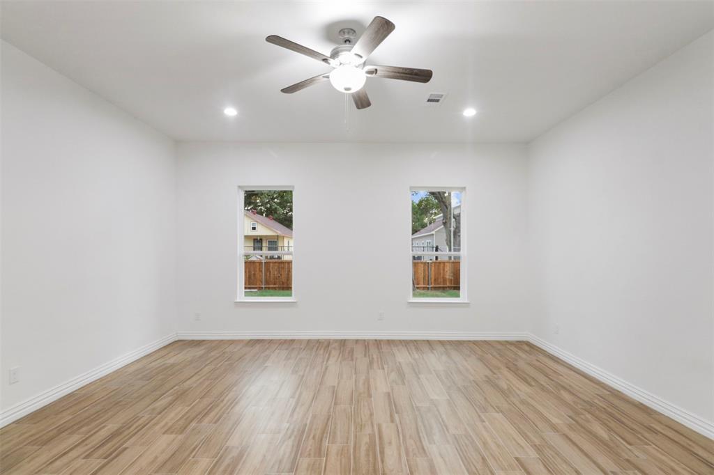 Room featuring wood-finish flooring, two windows, recessed lighting, a ceiling fan with integrated lighting, and white baseboards