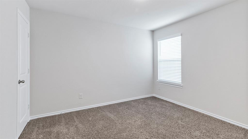 Room featuring light gray walls, gray carpeting, a single window with white blinds, and a white interior door