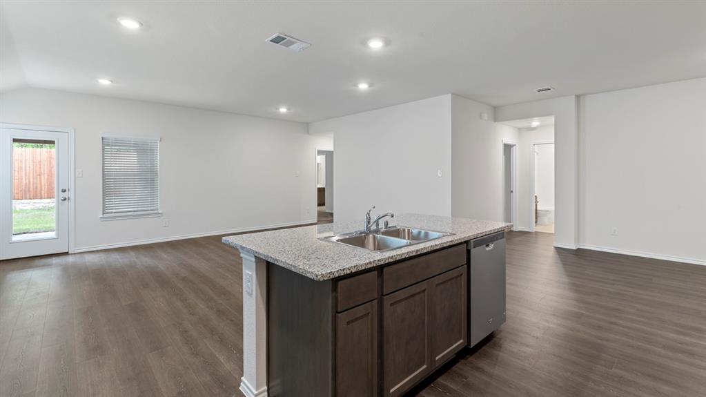Kitchen island with granite-finish countertop, dual basin sink, and stainless steel dishwasher