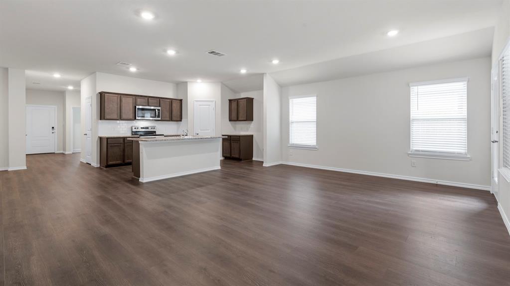 Open-concept living space featuring wood-finish flooring, recessed lighting, and a kitchen island with stone countertops
