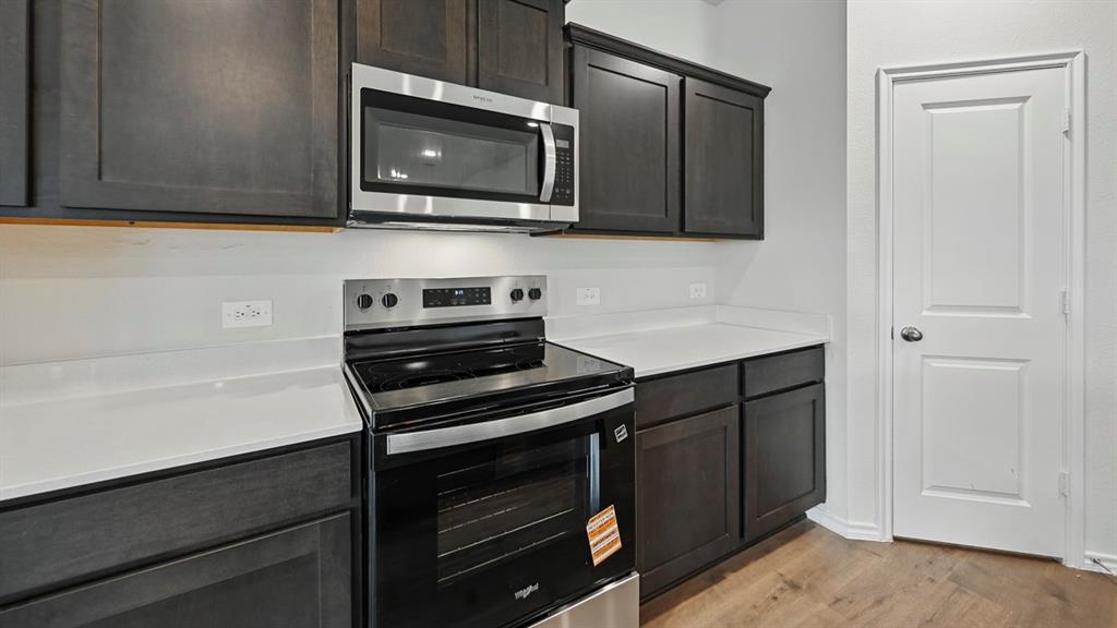 Kitchen featuring dark wood-finish cabinetry, light countertops, and stainless steel appliances