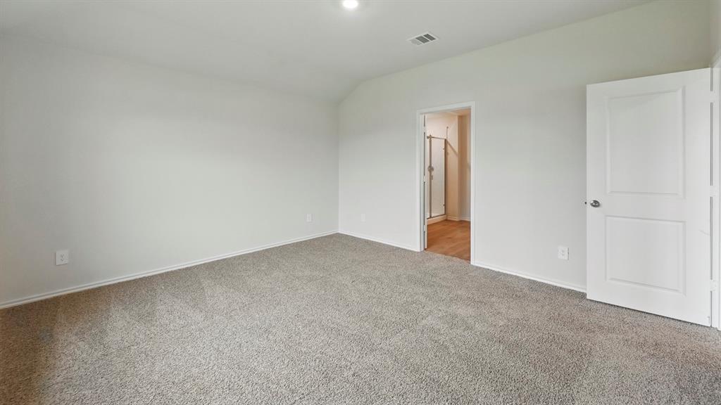 Spacious room featuring neutral carpeting, a white interior door with panel detailing, and recessed lighting