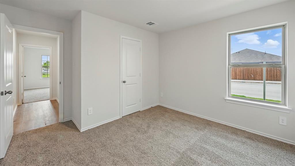 Bedroom featuring neutral-toned carpeting, a window with white trim, and light-colored walls