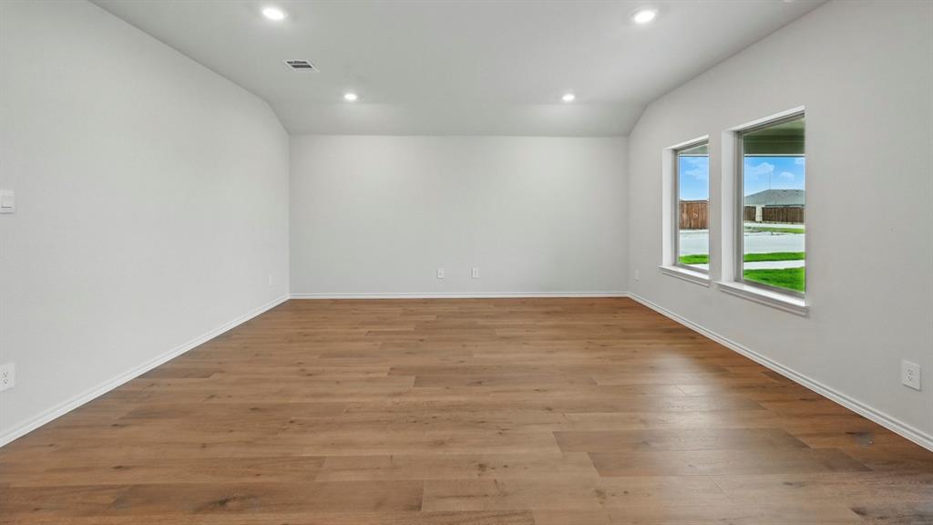 Spacious room featuring wood-finish flooring, two large windows, recessed lighting, white baseboards, and neutral wall paint
