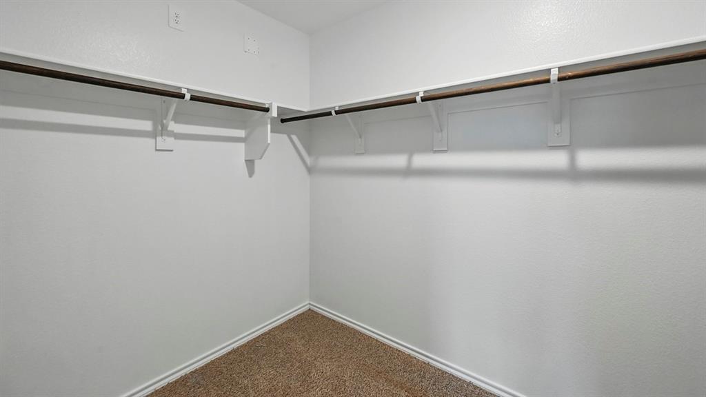 Walk-in closet featuring carpet flooring, crisp white walls, and dual-level hanging rods