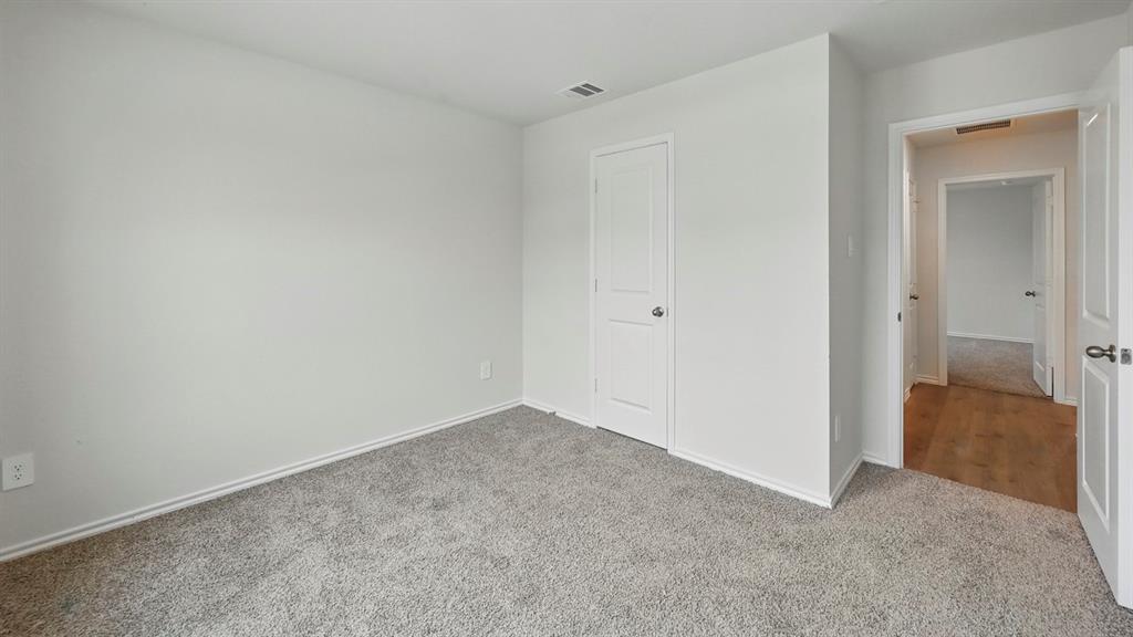 Interior room featuring light gray carpet, white walls, white trim, and a white interior door with a silver knob Interior room featuring light gray carpet, white walls, white trim, and a white interior door with a silver knob