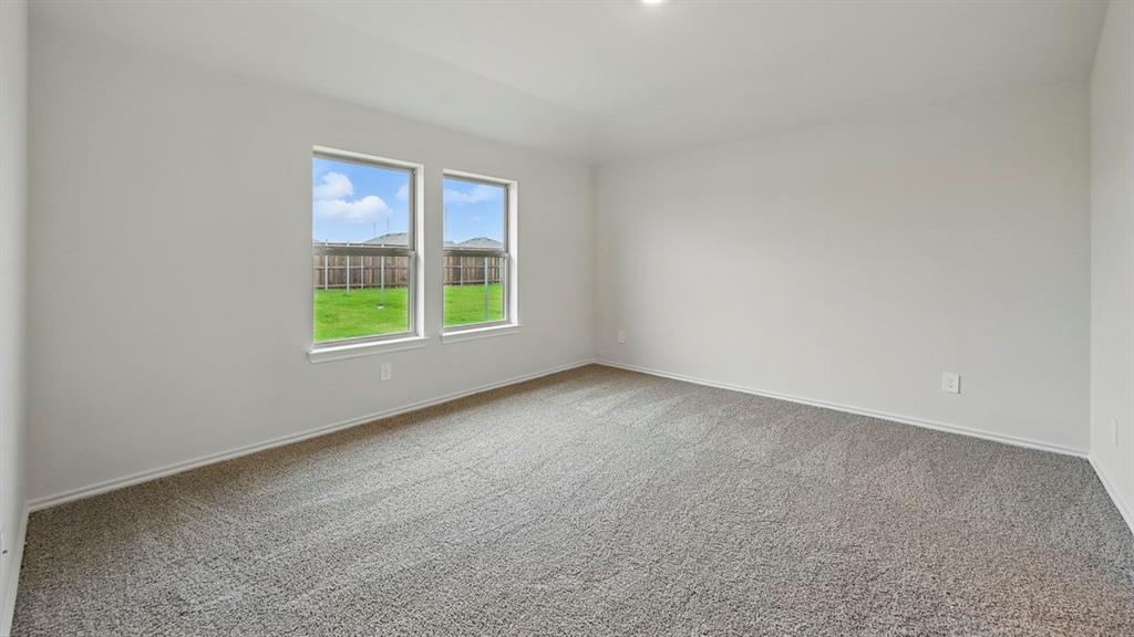 Spacious interior featuring neutral walls, gray carpet, and two bright windows with white trim