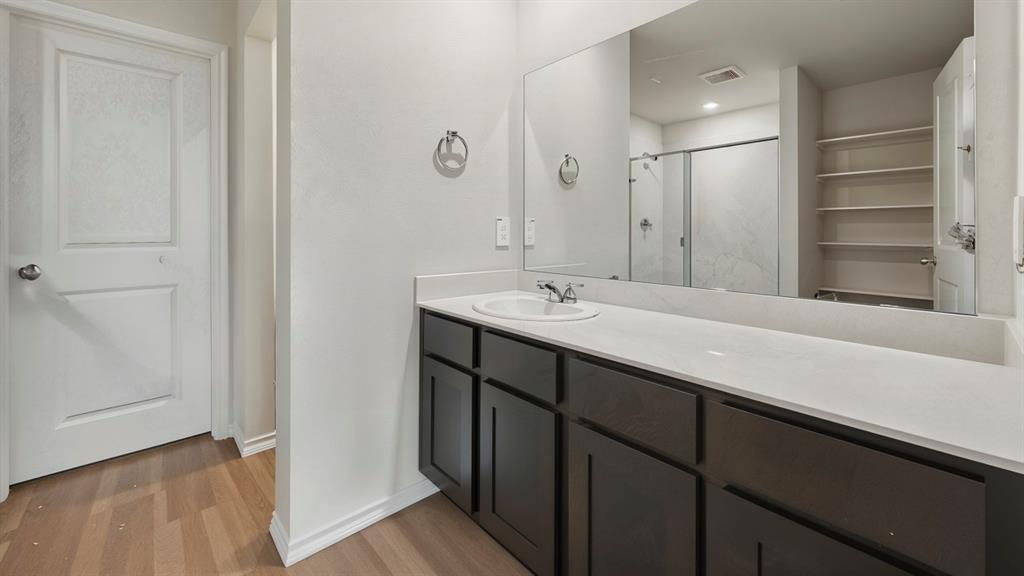 Bathroom featuring an extended vanity with dark wood-finish cabinetry and a light-toned countertop Bathroom featuring an extended vanity with dark wood-finish cabinetry and a light-toned countertop