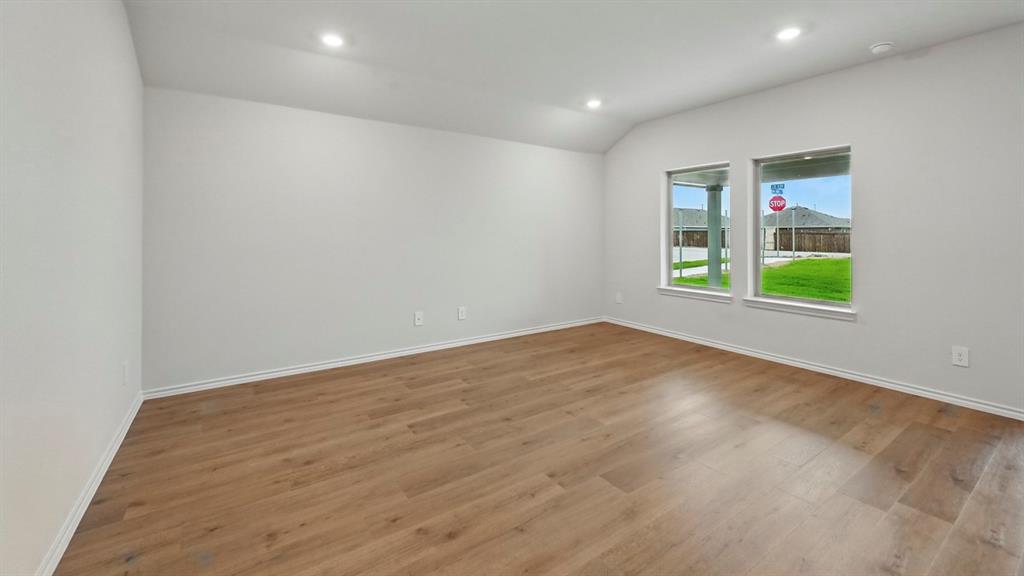 Spacious room with wood-finish flooring, white baseboards, recessed lighting, and two large windows