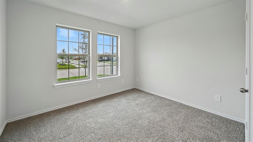 Neutral wall paint, two large windows with grid panes, gray carpet flooring, white baseboards, and a white interior door Neutral wall paint, two large windows with grid panes, gray carpet flooring, white baseboards, and a white interior door
