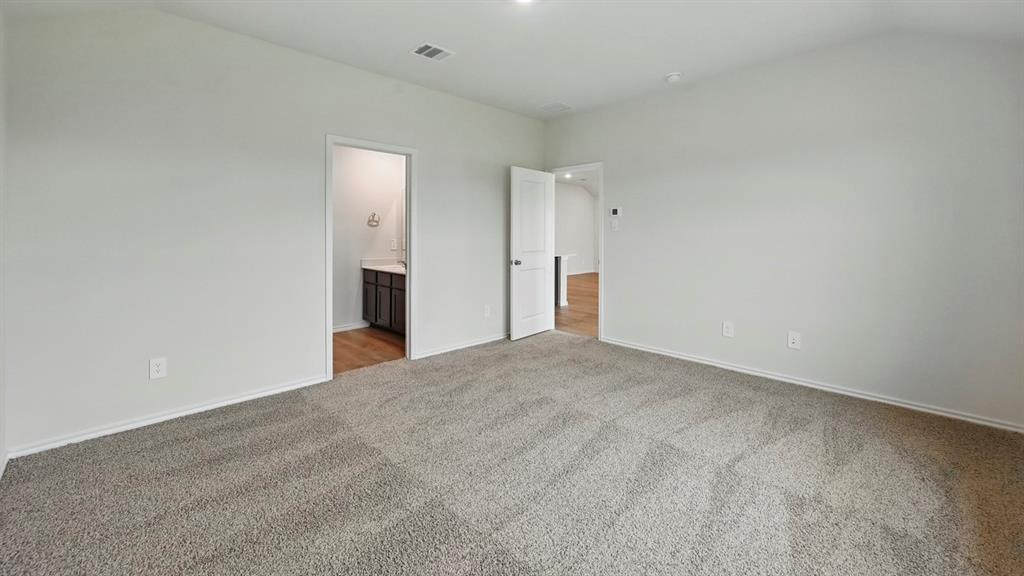 Spacious room featuring neutral carpeting, light-toned walls, and an overhead light fixture