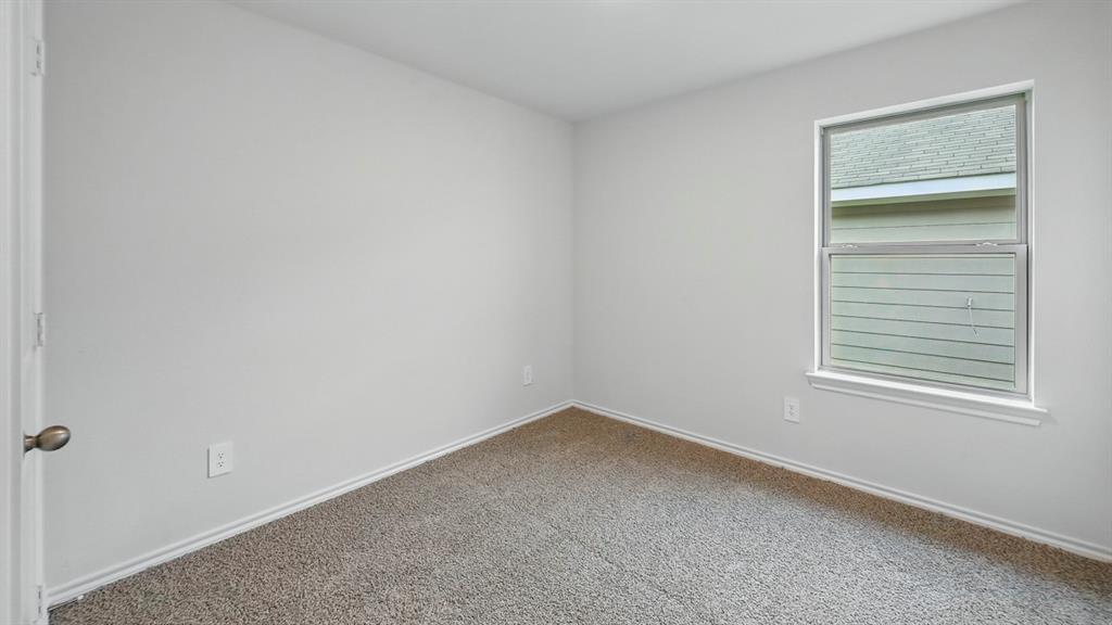 Neutral color palette room featuring light gray walls, plush gray carpet, a single window, and a white baseboard trim